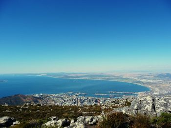 Aerial view of city by sea against clear blue sky