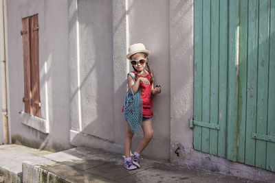 Full length of fashionable girl standing by wall outdoors