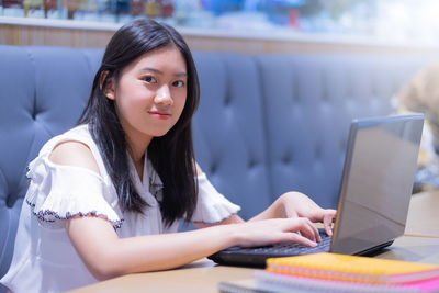 Portrait of young woman using phone on table