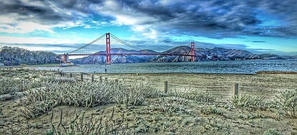 Bridge over river against cloudy sky