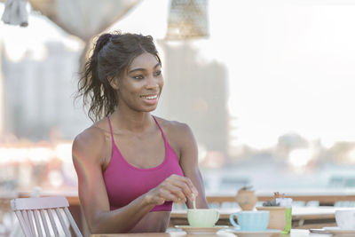 Portrait of smiling young woman sitting on table at cafe