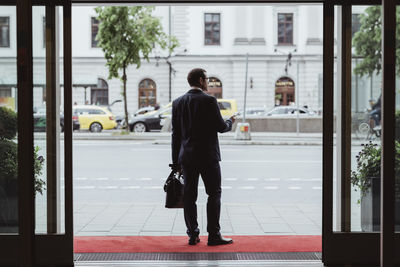 Full length of businessman with bag looking away in city