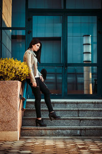 Side view of young woman standing on steps