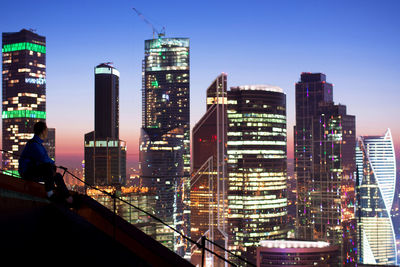 Illuminated buildings in city against clear sky at night