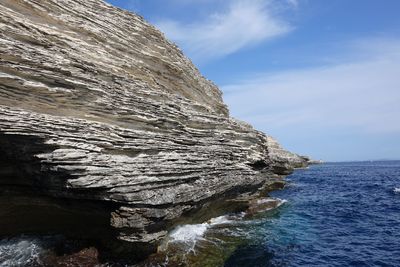 Rock formation in sea against sky