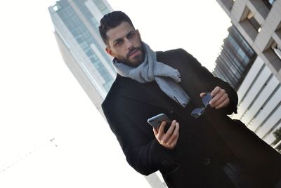 Portrait of man with mobile phone in city