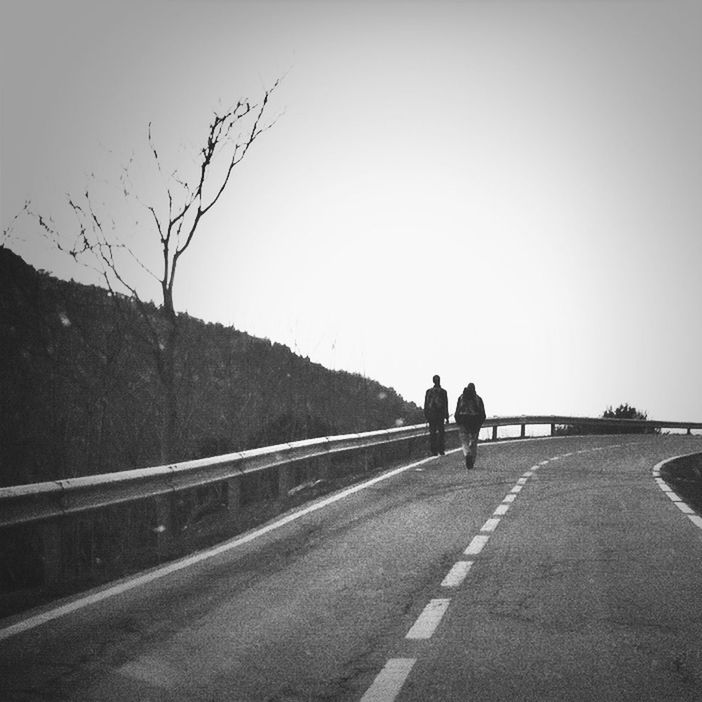 the way forward, road, clear sky, transportation, rear view, walking, copy space, full length, men, lifestyles, country road, diminishing perspective, leisure activity, sky, street, vanishing point, road marking, person