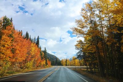 Road amidst trees against sky during autumn