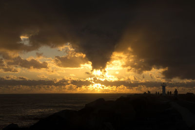 Scenic view of sea against cloudy sky during sunset