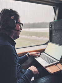 Rear view of young woman using laptop while sitting in car