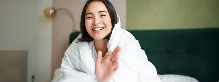 Portrait of young woman sitting on bed at home