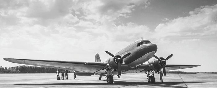 Airplane at airport runway against sky