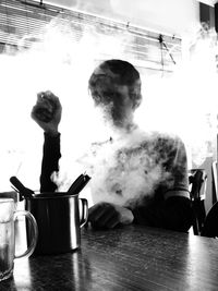 Man smoking cigarette on table in kitchen