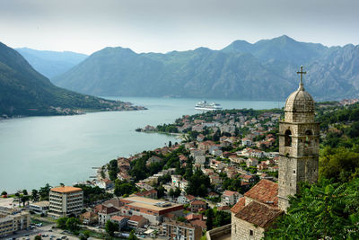 Aerial view of village by river against mountains 