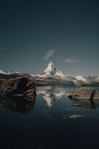 Scenic view of lake by snowcapped mountain against sky