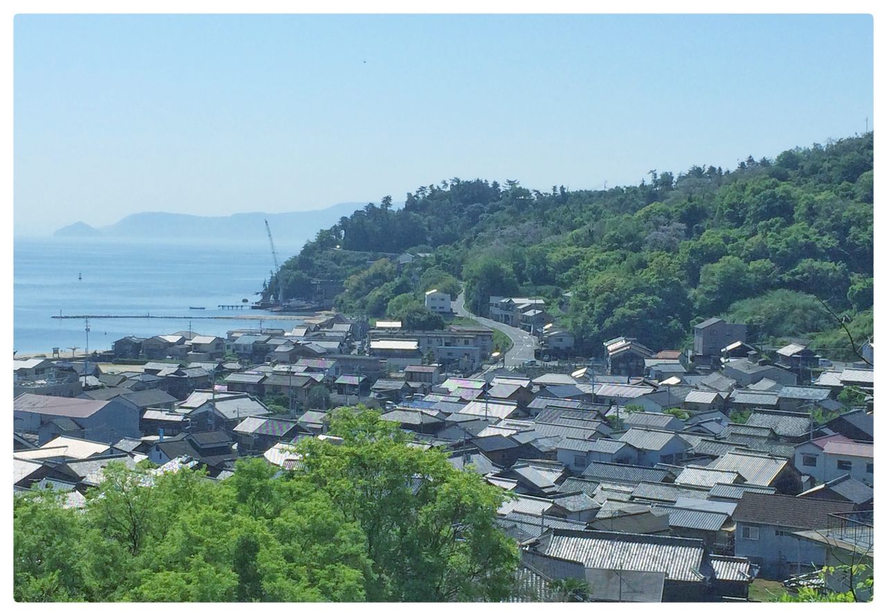 transfer print, water, auto post production filter, clear sky, tree, mountain, sea, building exterior, scenics, built structure, high angle view, copy space, architecture, tranquil scene, tranquility, nature, blue, beauty in nature, town, day