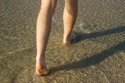 Low section of person legs on sand at beach