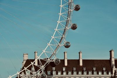 Low angle view of ferris wheel against buildings in city