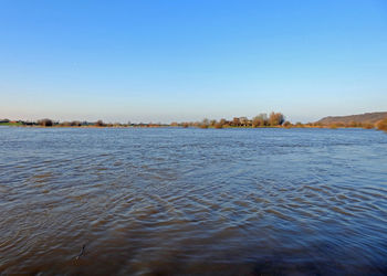 Scenic view of lake against clear blue sky