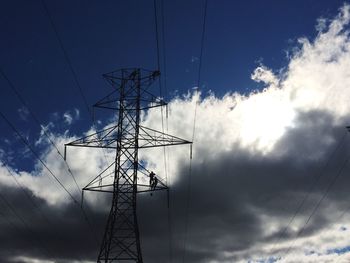 Low angle view of silhouette electricity pylon against sky