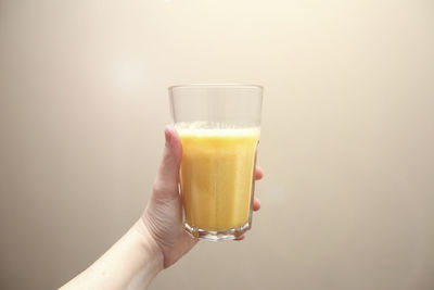 Close-up of hand holding drink against white background