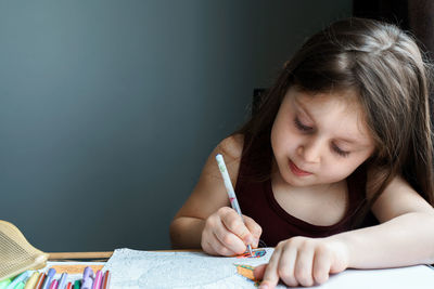 Close-up of cute girl drawing on book at home