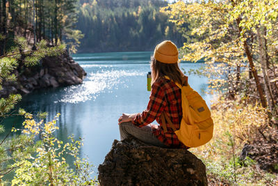 Rear view of woman sitting on rock