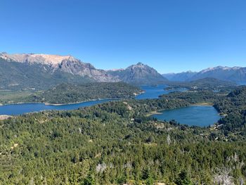 Scenic view of lake and mountains against clear blue sky