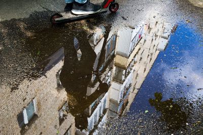 Low section of person in puddle on road