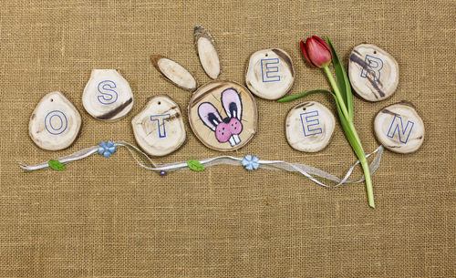 Directly above view of rabbit head with alphabets and tulip on jute