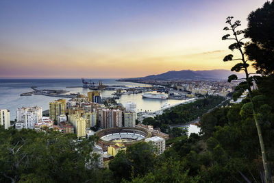 Aerial view of cityscape by harbor against sky