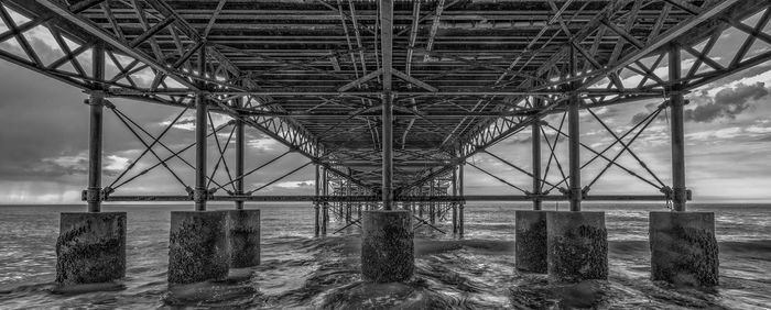 Bridge over sea against cloudy sky