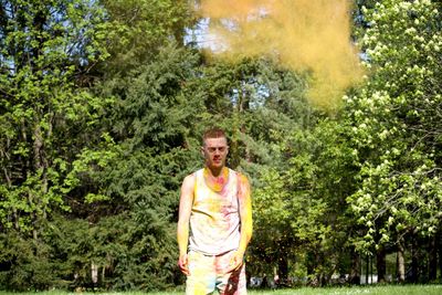 Portrait of man covered with powder paint while standing against trees