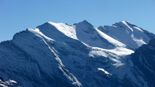 Scenic view of snowcapped mountains against clear blue sky