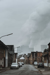 Cars on road amidst buildings in city against sky