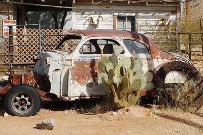 Abandoned car by old house during sunny day