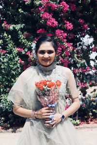 Woman holding flower bouquet against wall