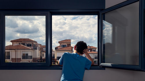 Rear view of woman standing by window