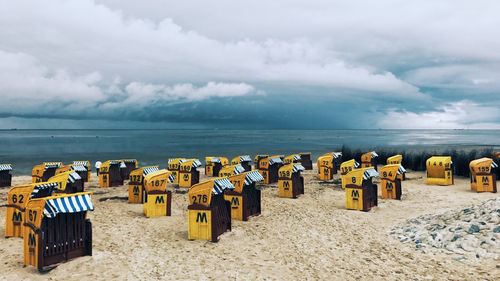 Deck chairs on beach against sky