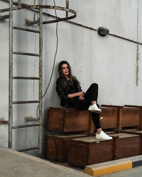Young woman sitting against wall