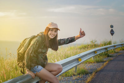 Portrait of smiling young woman gesturing on road 