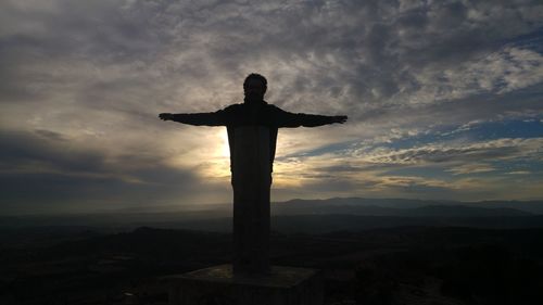 Silhouette statue of cross against sky during sunset