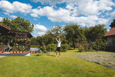 Rear view of woman walking on field against sky