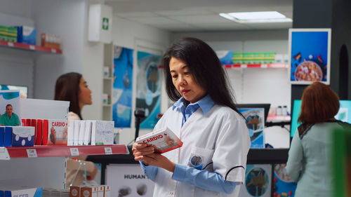 Portrait of young woman using mobile phone while standing in laboratory