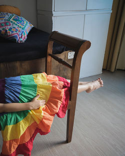  little girl lying on the long chair in the living-room with a beautiful rainbow long dress.