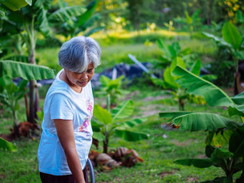 Side view of young man standing against plants