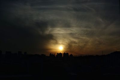 Silhouette of city against dramatic sky