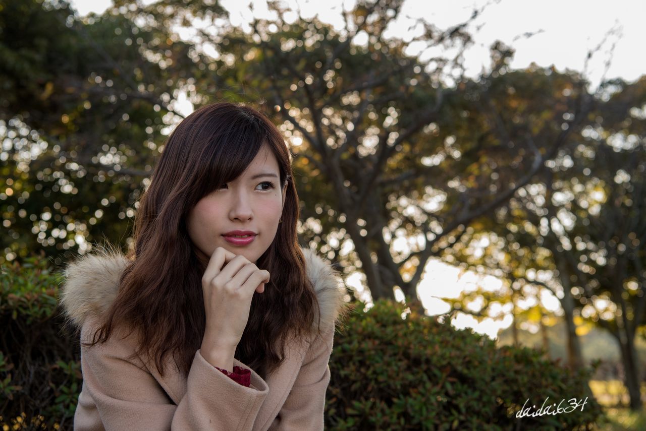 young adult, one person, tree, looking at camera, portrait, long hair, beautiful woman, one young woman only, young women, focus on foreground, headshot, front view, bangs, outdoors, only women, day, real people, smiling, medium-length hair, one woman only, happiness, beauty, adult, adults only, close-up, nature, people