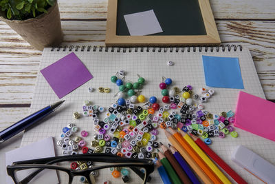 High angle view of alphabet beads with school supplies on table