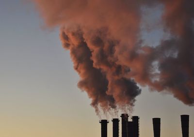 Low angle view of smoke emitting from factory against sky